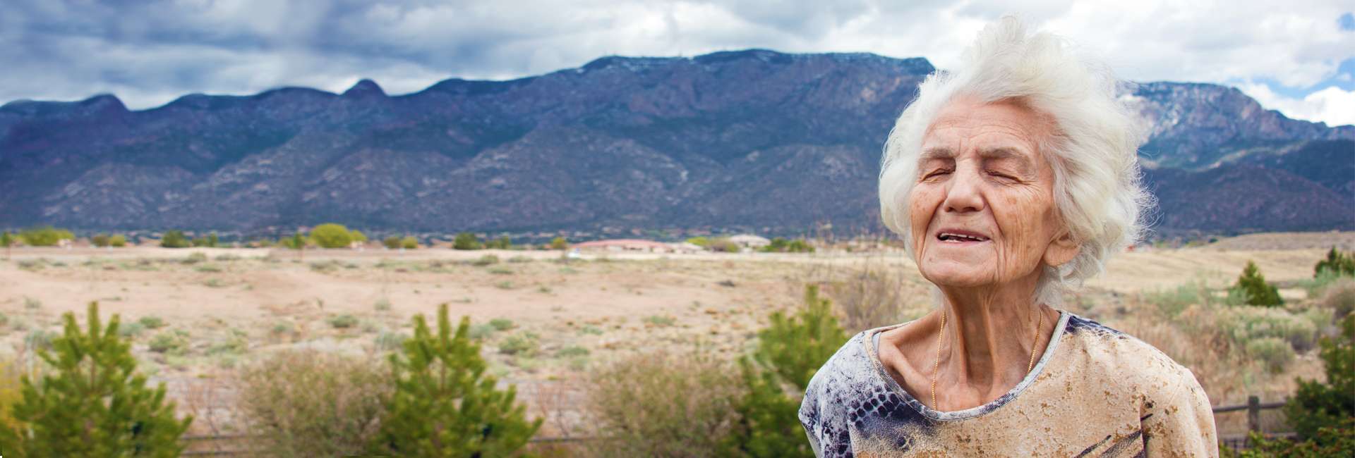 Elderly woman enjoying the breeze in the desert.